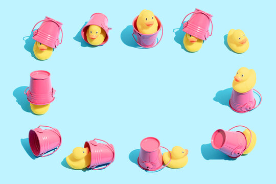Yellow rubber ducky and pink bucket in different funny poses on pastel blue backround. Minimal summer vacation composition with copy space.