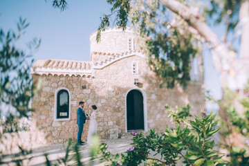 Fototapeta na wymiar Wedding in Cyprus. A couple of newlyweds are photographed near the walls of the Temple of Elijah the Prophet in Protaras.