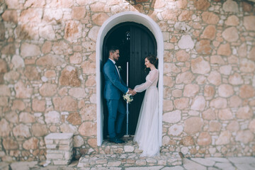 Fototapeta na wymiar Wedding in Cyprus. A couple of newlyweds are photographed near the walls of the Temple of Elijah the Prophet in Protaras.