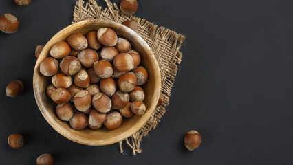 hazelnuts on a dark matte gray background close-up in a wooden plate, close-up, tom view, copy space