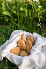 Composition of white flour buns in basket with white white cloth napkin on the green grass. High quality photo