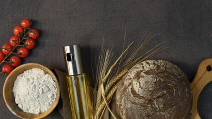 fresh dark yeast-free bread on a dark background surrounded by olive oil in a dispenser, fresh...