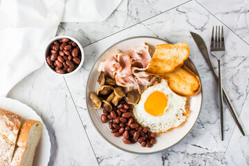 English breakfast with fried egg, bacon, beans, mushrooms and toast on a plate. Top view