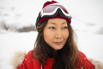 Asian woman in snowboard suit. Sportswoman on a mountain with a snowboard in the hands. Concept on winter sports.