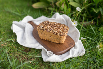 homemade grey bread with seeds on the wood board with the white cloth napkin on the green grass. High quality photo