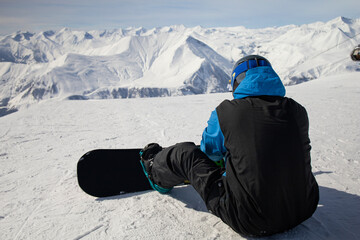 Back view of snowboarder at mountains background in ski resort 