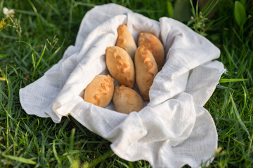 Composition of white flour buns in basket with white white cloth napkin on the green grass. High quality photo