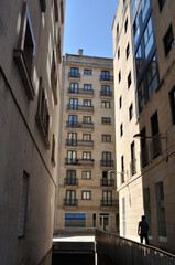 Fototapeta na wymiar Rua estreita de cidade com prédios altos e uma pessoa em movimento, Vigo, Espanha 
