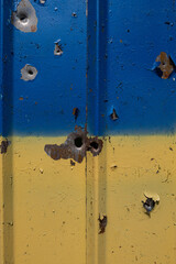 Shot and shrapnel holes on the wall in the colors of the Ukrainian flag