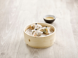 Steamed Black Truffle and Assorted Mushroom Dumpling served in a wooden bowl side view on grey marble background