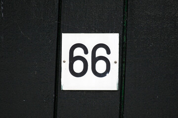 House number 66 sign on a dark wood  wall