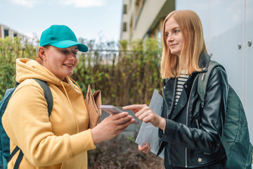 Delivery woman giving paper mail letter parcel to recipient next to the business building