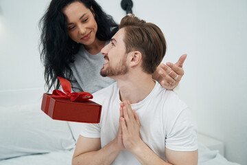 Joyous young man receiving gift from woman