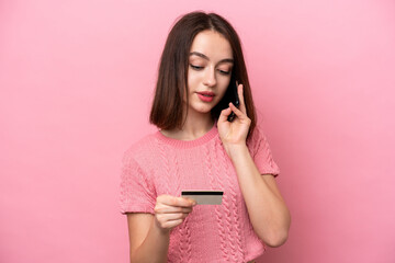 Fototapeta premium Young Ukrainian woman isolated on pink background buying with the mobile with a credit card