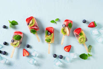 Fruit ice cream, colorful summer dessert on stick with strawberry, blueberry, kiwi and mint leaf