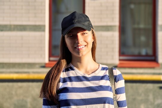 Outdoor portrait of teenage girl in black cap, city street background