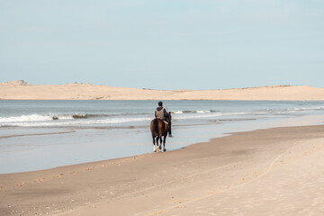 Person on horseback on the beach of Barra de Valizas with the dunes in the background