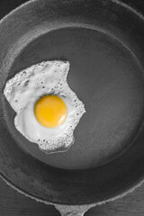 scrambled eggs in a cast iron skillet. Isolated on dark painted wood from above.
