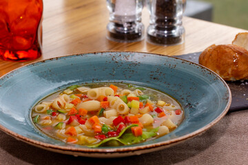 A bowl of minestrone soup with crackers on rustic vintage background