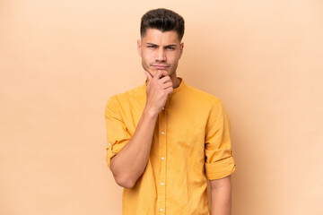 Young caucasian man isolated on beige background thinking