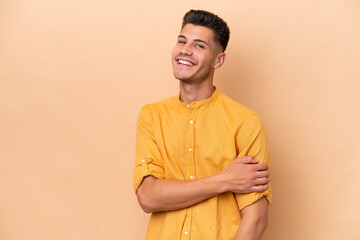 Young caucasian man isolated on beige background laughing