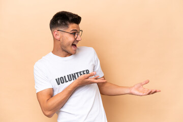 Young volunteer caucasian man isolated on beige background with surprise facial expression