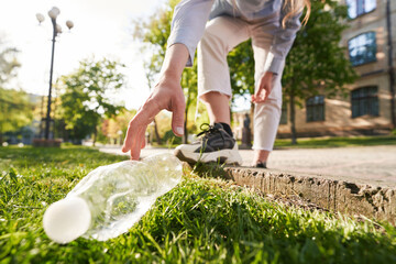 Woman picking up plastic litter in city