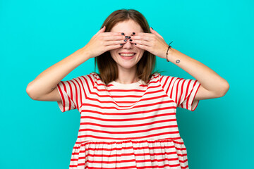 Young English woman isolated on blue background covering eyes by hands and smiling - obrazy, fototapety, plakaty