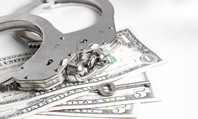 Police handcuffs with a key are on the low denomination USD bills. Minor crimes. Police handcuffs, the penalty of imprisonment for a crime.