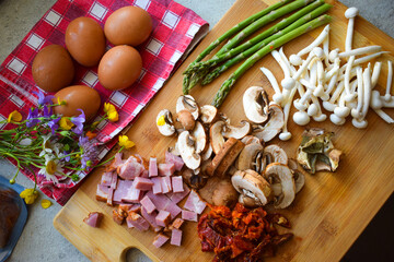 Mushrooms, asparagus and bacon cut on a wooden board.