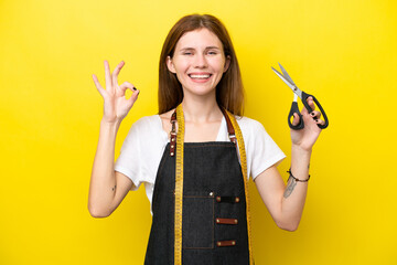 Young seamstress English woman isolated on yellow background showing ok sign with fingers