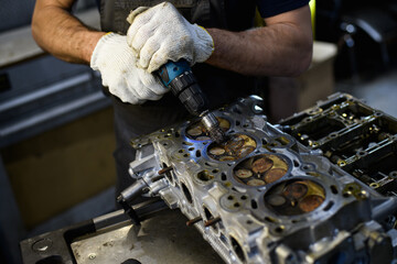 Partial shot of mechanic holding screwdriver near valves of damaged car engine in garage 
