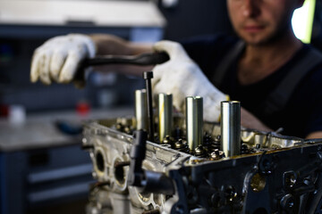 Partial view of workman standing near damager car motor in service station 