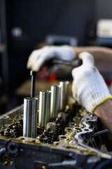 Faceless shot of mechanic in gloves fixing car motor after accident in garage 