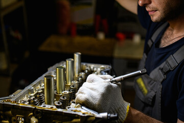 Partial shot of workman in glove repairing damaged car engine in garage 