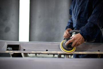 Partial view of workman polishing car part in auto service station 