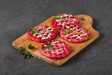 Round beetroot waffles, on a wooden board. Dark gray background