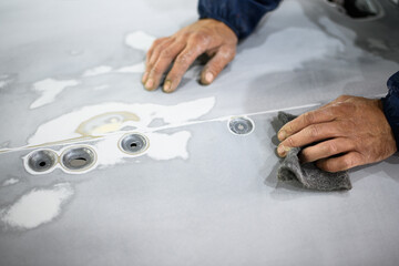 Faceless shot of workman sanding car in auto service station 