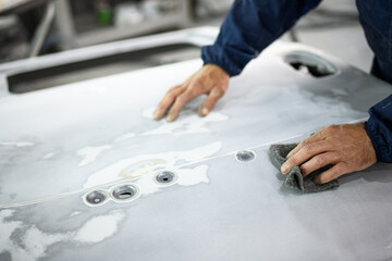 Partial shot of repairman sanding varnish from car part in auto service 