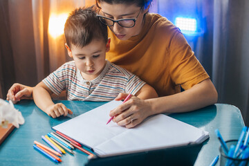Beautiful mother teaching her boy how to count and write at home. Education, learning, study. Developing arithmetic abilities.
