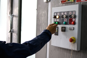 Partial shot of workman switching buttons on control panel in painting chamber of auto service 