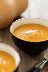 Side view of bowl with delicious pumpkin soup and spoons on a wooden table