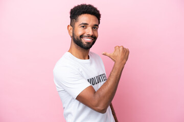 Young volunteer man isolated on pink background proud and self-satisfied