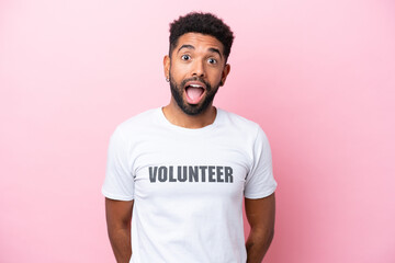 Young volunteer man isolated on pink background with surprise facial expression