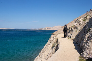 A girl walking on a trail on the shore with blue sea