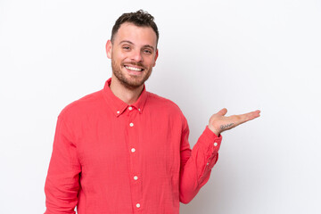 Young Brazilian man isolated on white background holding copyspace imaginary on the palm to insert an ad