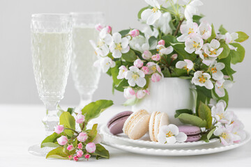 Beautiful composition with delicious French macarons and spring flowers in a white cup. Sweet dessert, early spring white and pink flowers, wedding decor, bride morning