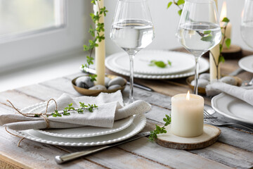 Rustic zero waste wedding decor with natural elements. Wooden table, candles, linen napkins, branches with green leaves. Eco-friendly decoration for the special dinner. Romantic and cozy place