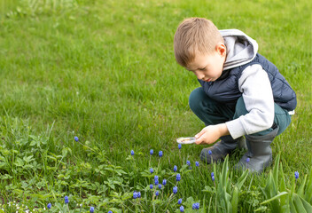 A little boy with a magnifying glass is studying the world around him