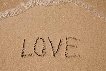 Love - handwritten on the soft beach sand.